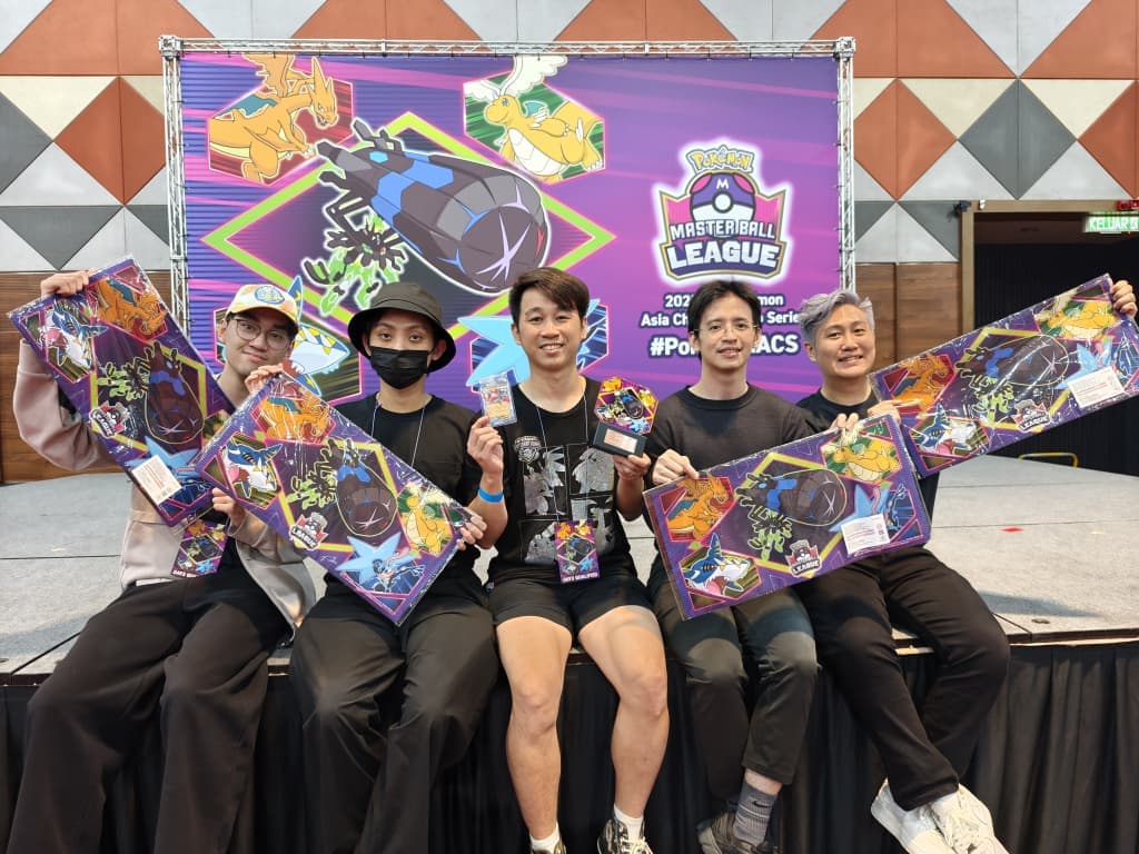 Team Monki members at the Master Ball League holding up prize playmats