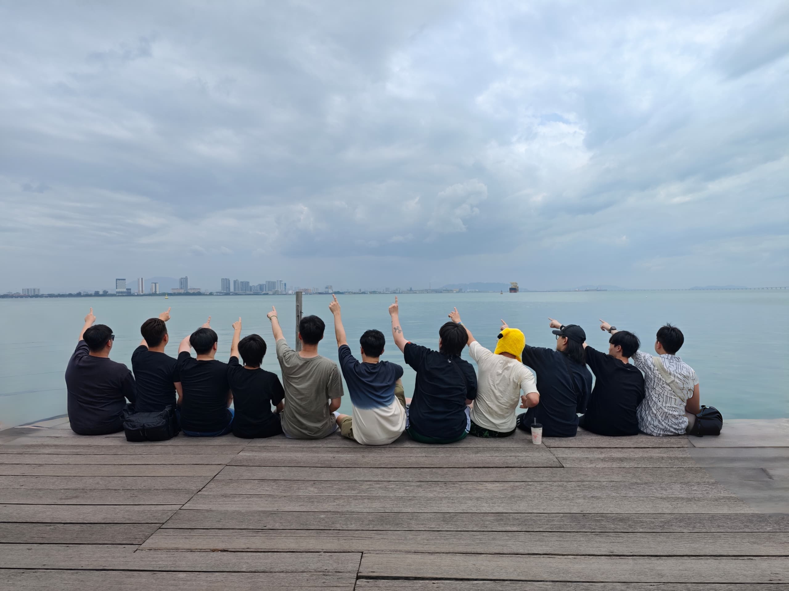 Team Monki members sitting on a pier, pointing out to sea